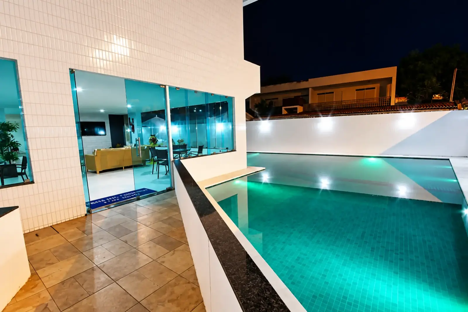 Piscina ao ar livre iluminada à noite ao lado do lounge do hotel
